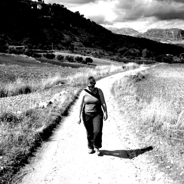 woman walking down a path surrounded by tall grass