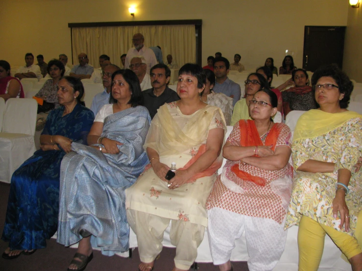 several women sitting on chairs in front of a crowd