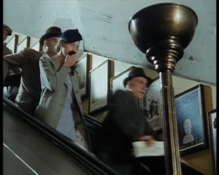 people standing on an escalator near a mirror