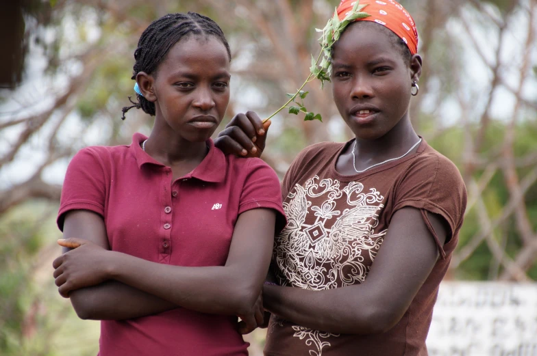 two girls in red shirts holding an item together