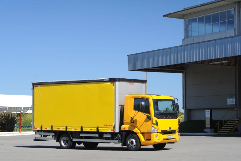 a yellow and white delivery truck in front of a building