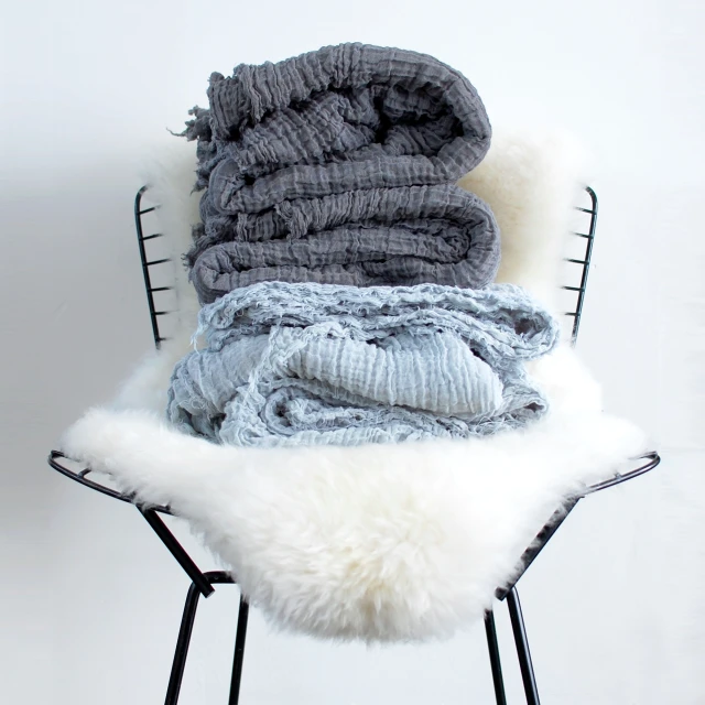 blankets and mittens lie on a chair in front of a white background