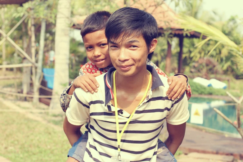 two boys stand next to each other near a pool