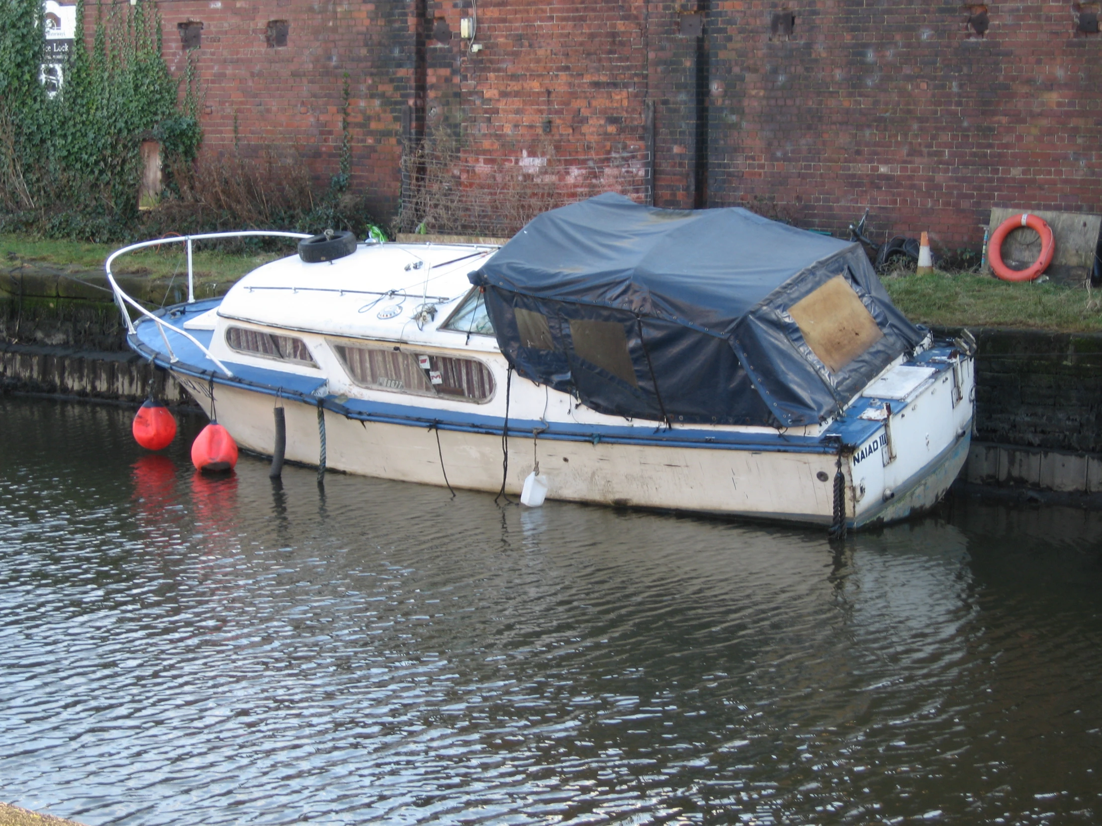 the small boat is moored next to a wall