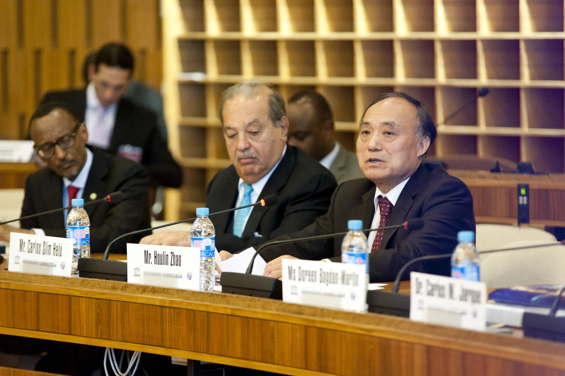 three men sitting at a meeting in a conference room