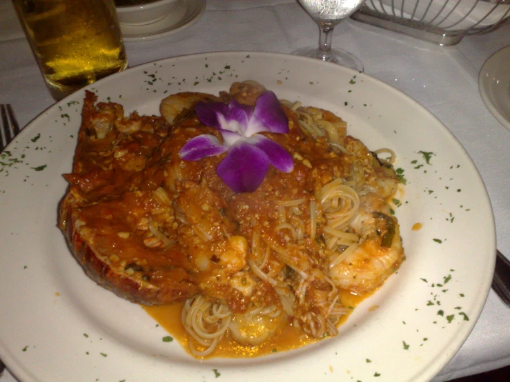 a white plate topped with pasta and meat covered in sauce