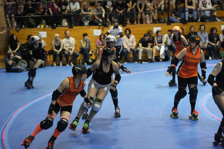 a group of rollerbladers skating on a blue floor