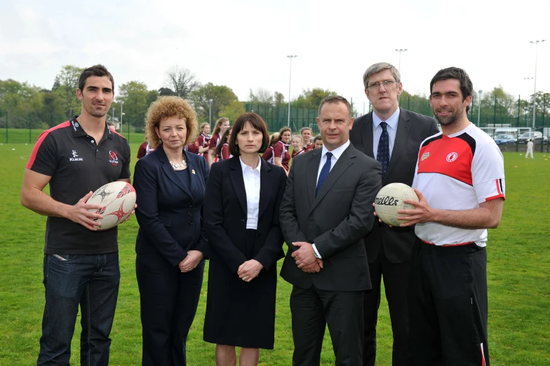 some men and women are holding soccer balls