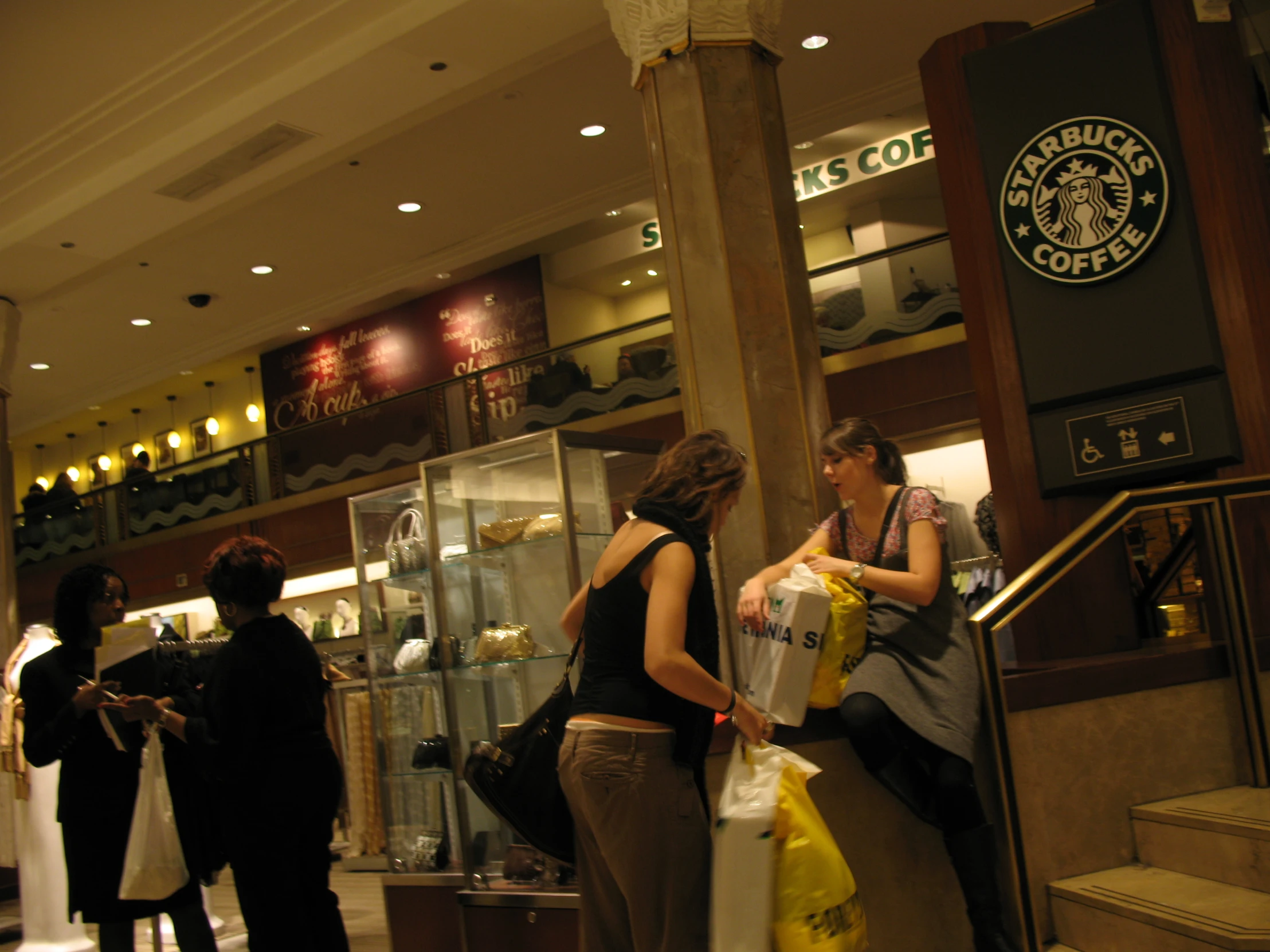 two women stand with bags near a starbucks