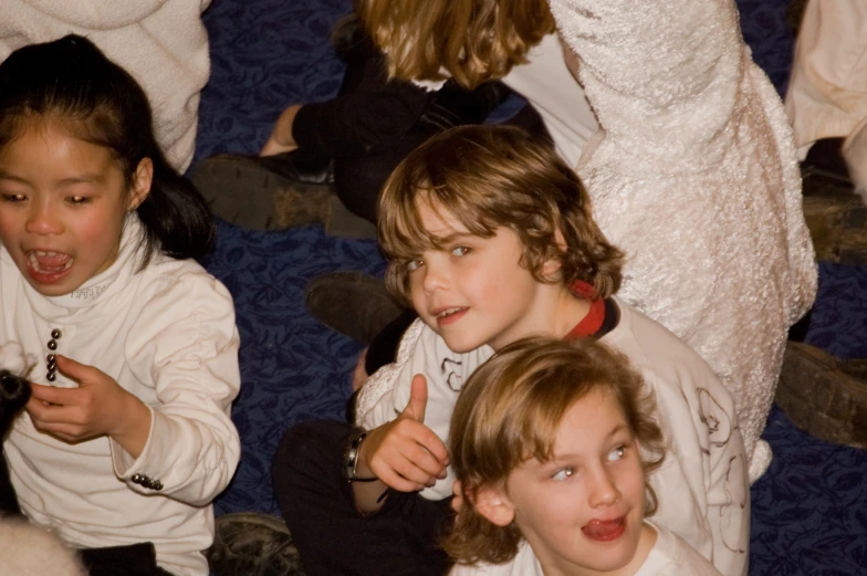 three children with cell phones sitting in a room