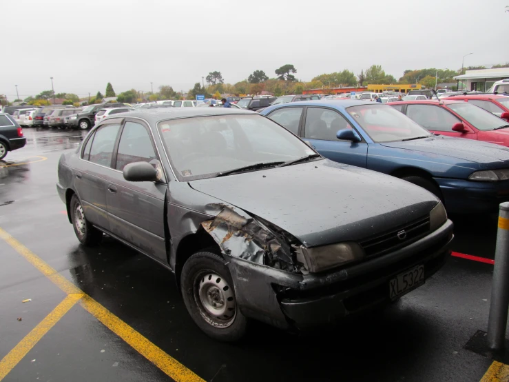 a car sitting in a parking lot with the hood smashed