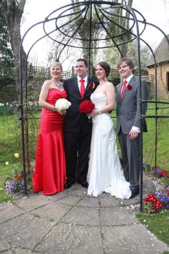 a couple and two bridesmaids are posing for a po in a garden