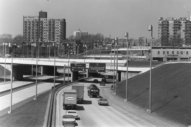 vehicles driving on an interstate overpass with buildings in the background