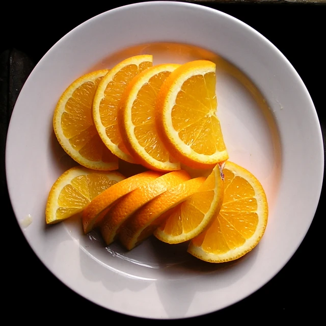 some sliced oranges on a white plate with some ice cream