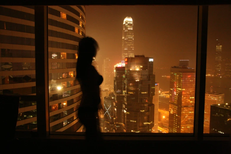 a girl stands near the window in a tall building
