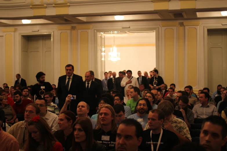 several people sitting in front of a large crowd of men and women