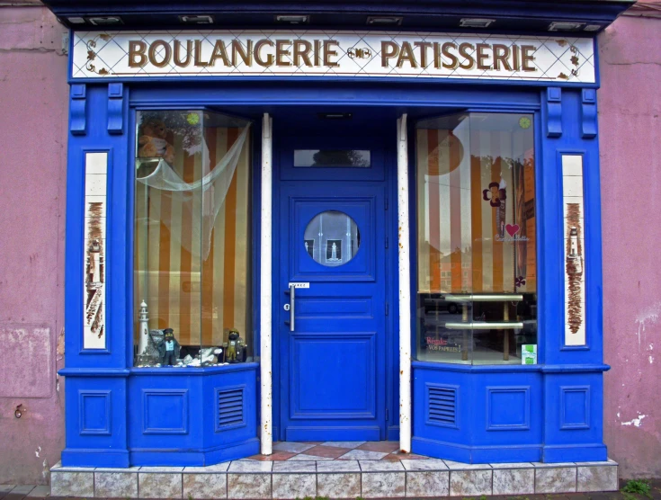 a blue shopfront has a blue door with french glass