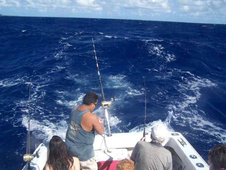 four people fishing off the bow of a boat in rough seas