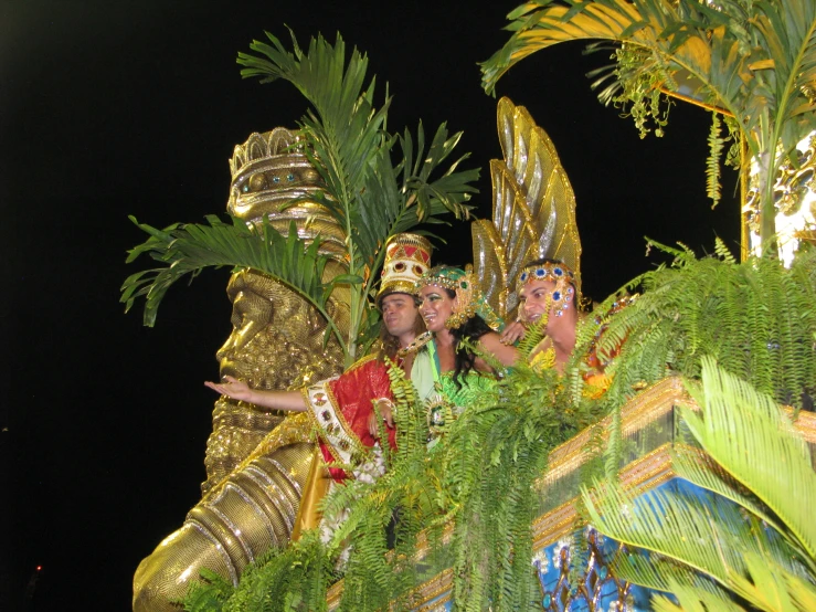 two women wearing elaborately decorated outfits ride on a float