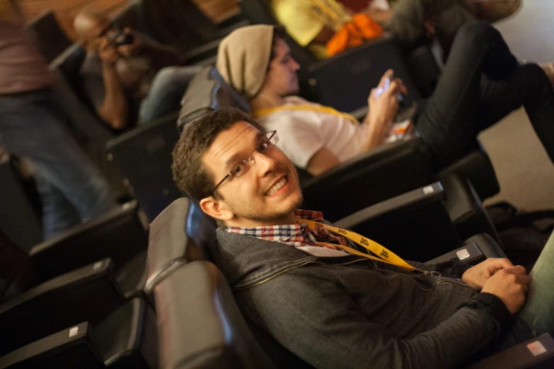 man sitting in an auditorium while someone uses his cell phone