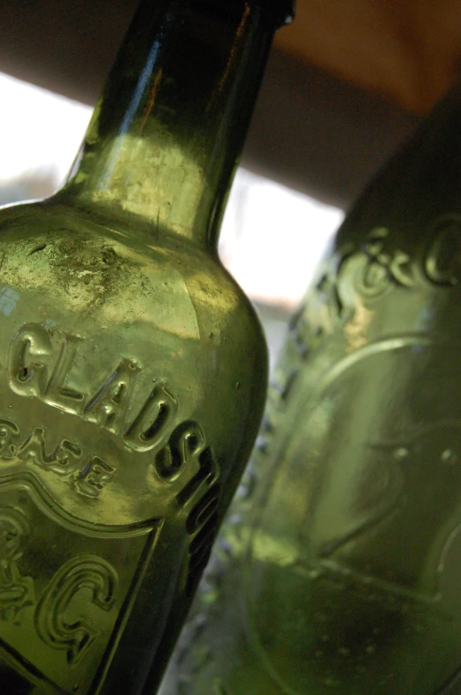 two green glass bottles with a logo of a company on it