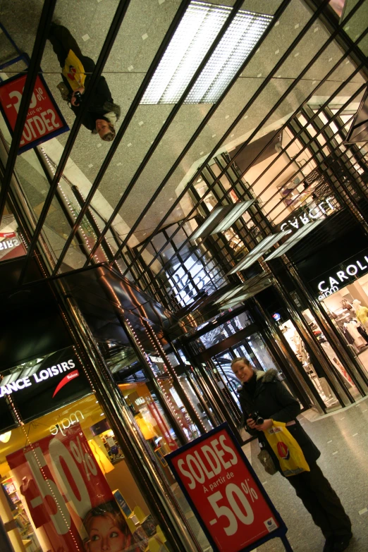 a woman walks by a store with signs advertising the sale