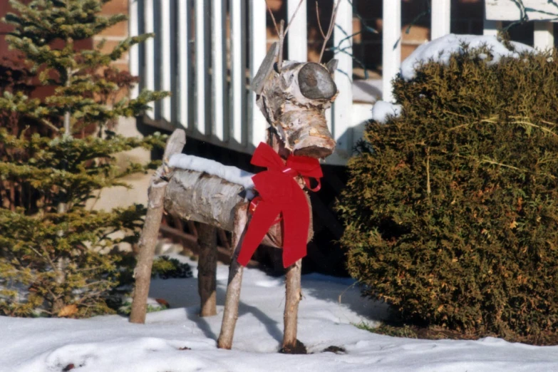 a wooden horse in the snow and red ribbon