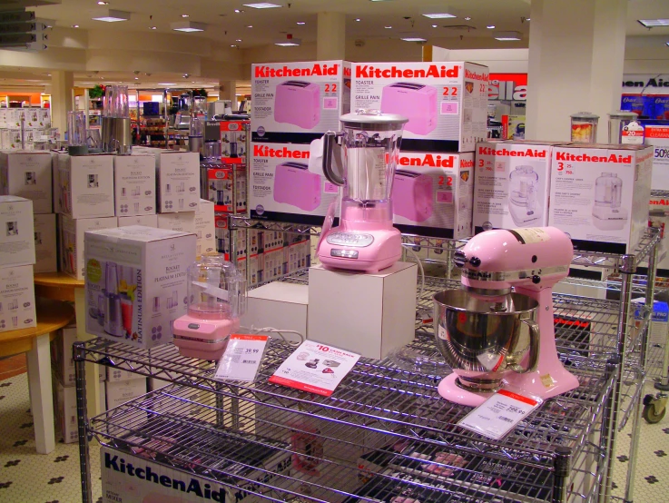 a kitchen aid stand in a store, full of pink mixers