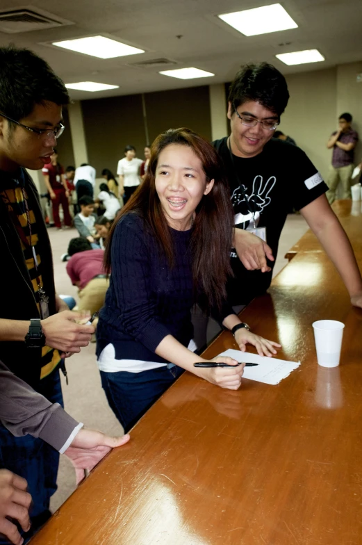 three people are sitting at a table with papers