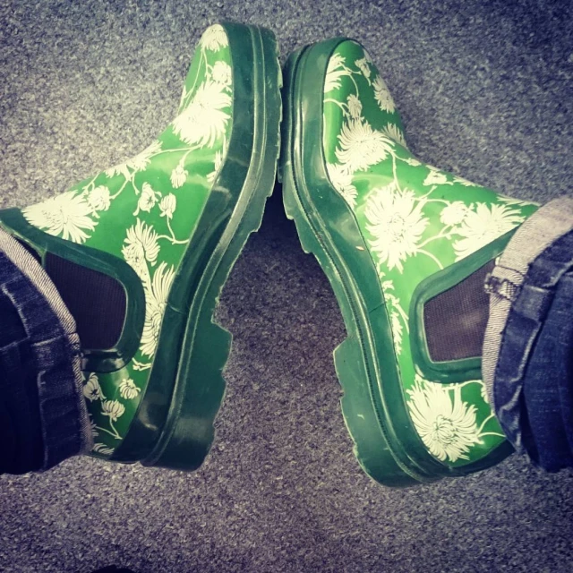 two feet wearing green floral print slippers