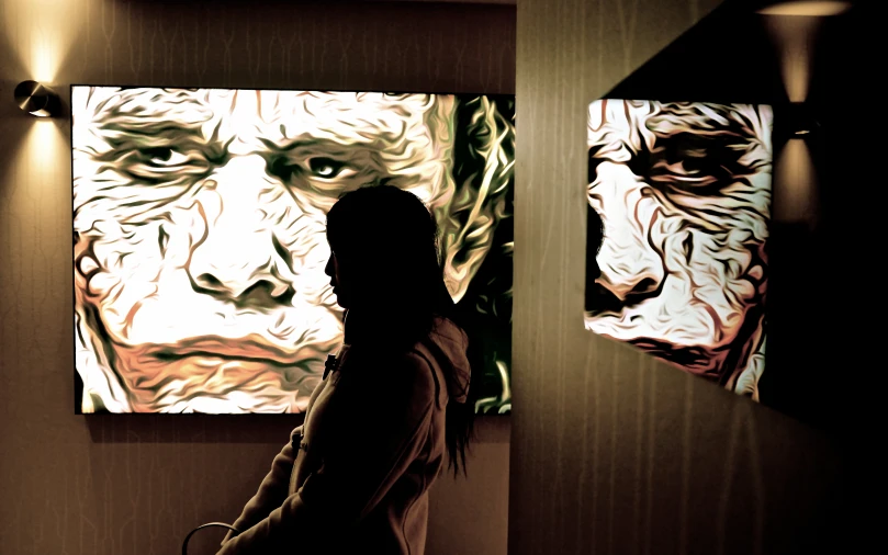 a woman standing next to paintings in an art gallery