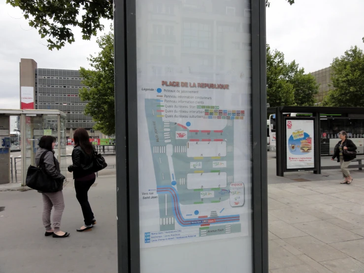 two people walk near a map in a city