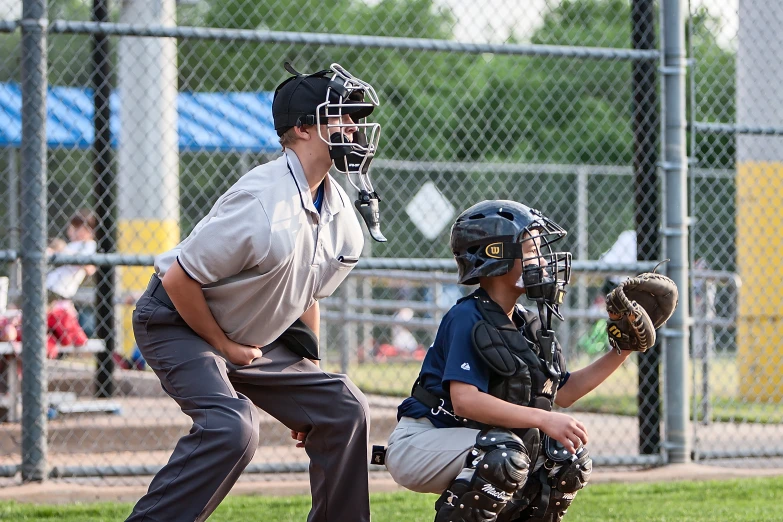 an umpire watches while a batter prepares to catch the ball