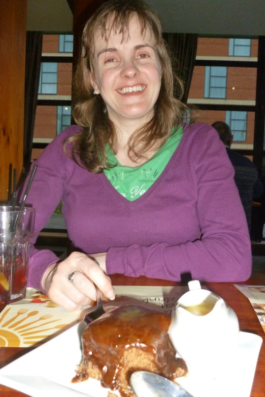 woman sitting at table eating food with utensils