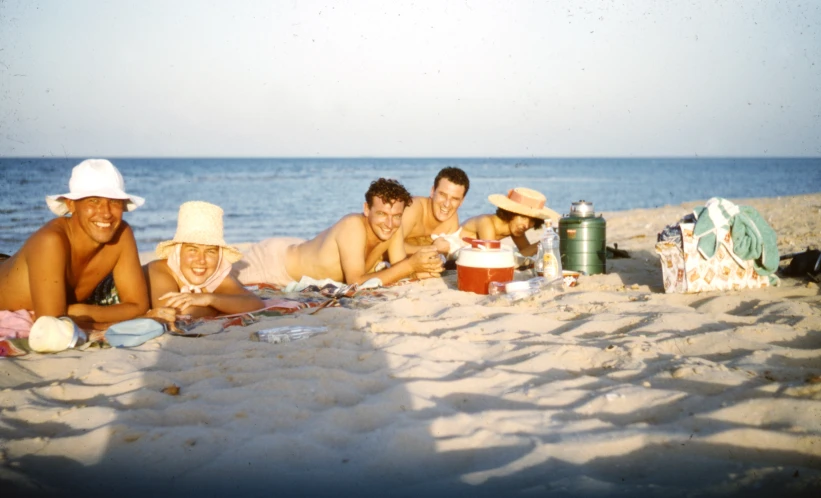 some people laying out on the sand by the ocean