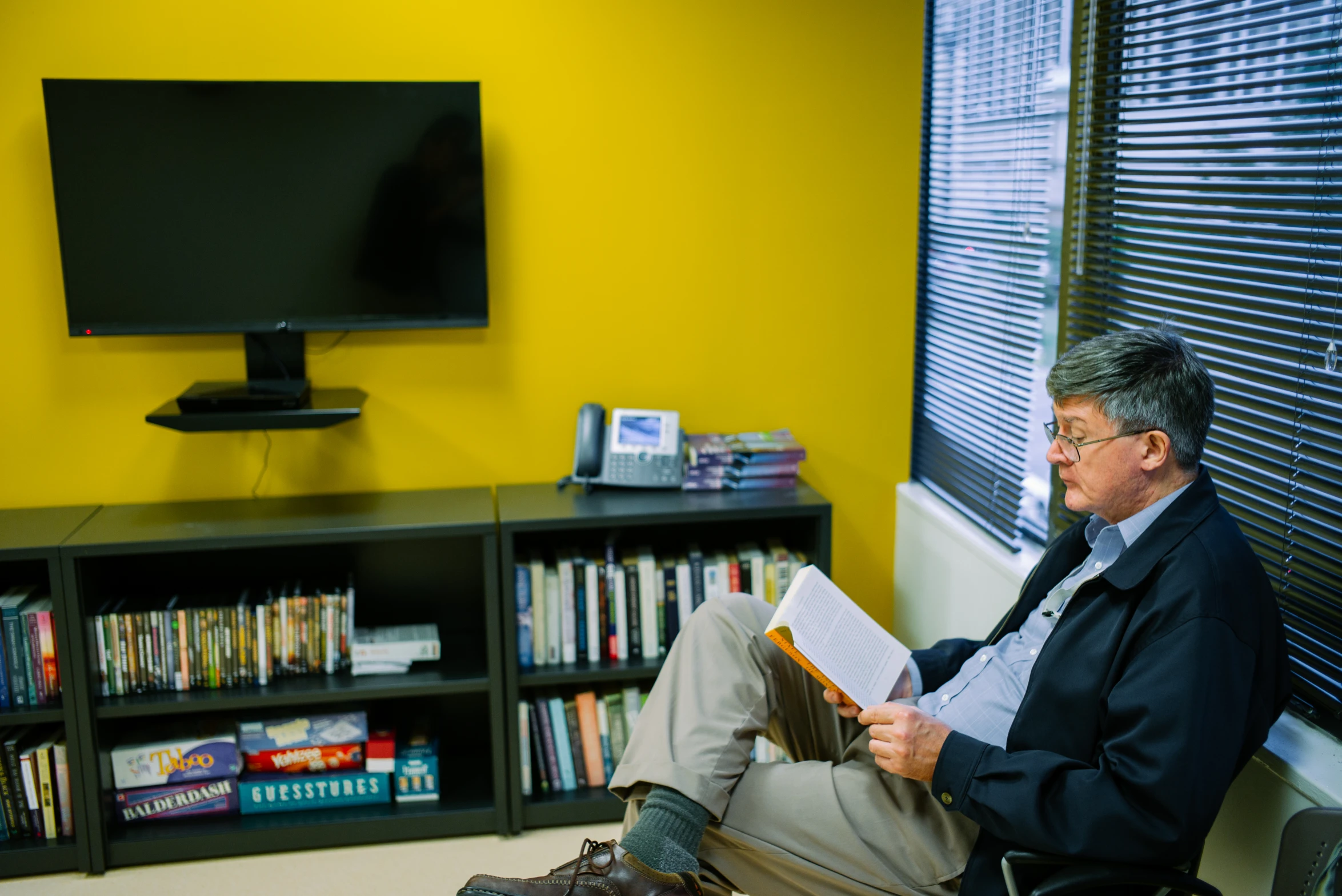 a man sitting on a chair with his legs crossed in front of him while reading