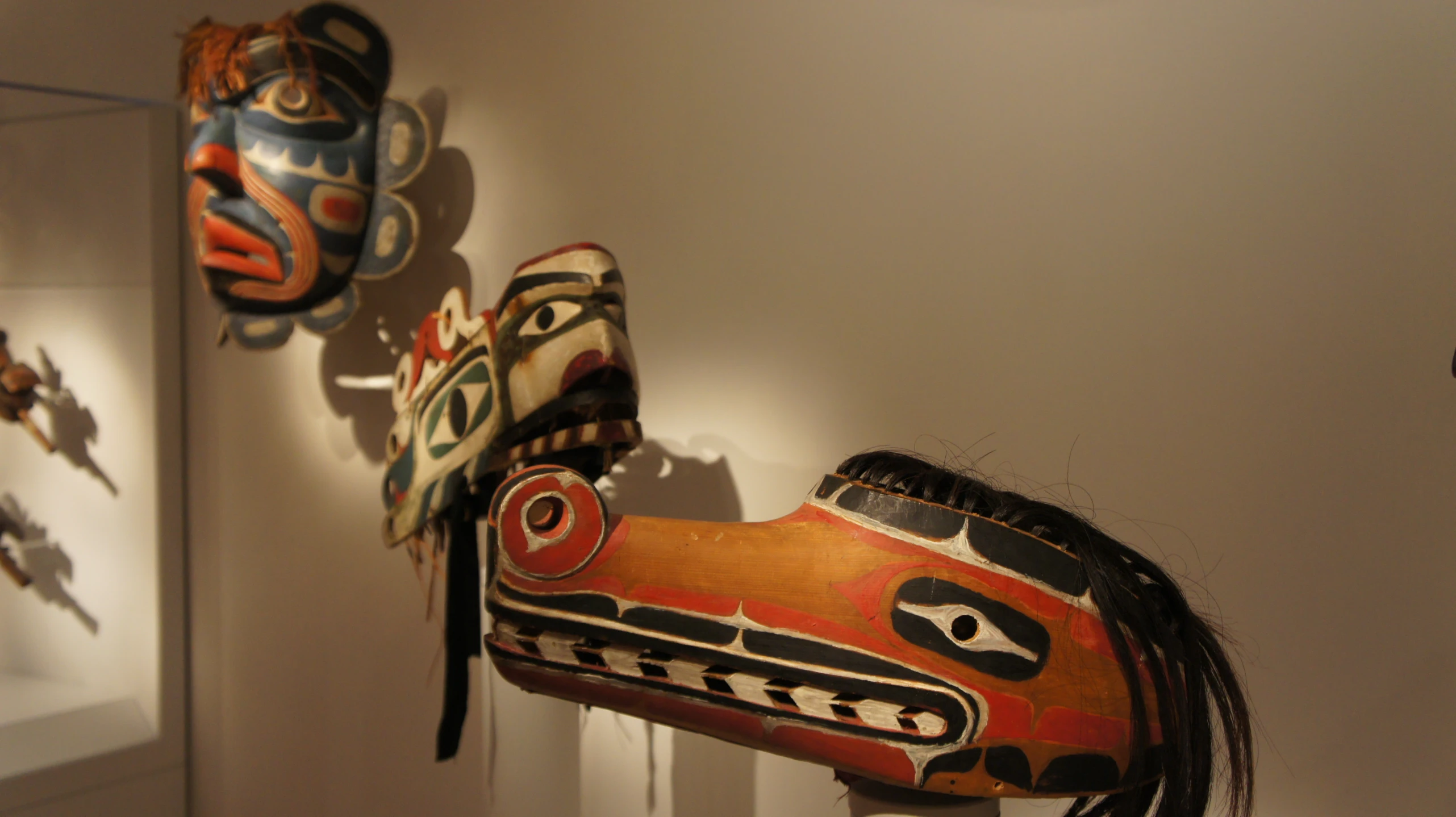 mask sculptures are displayed on the wall by each other