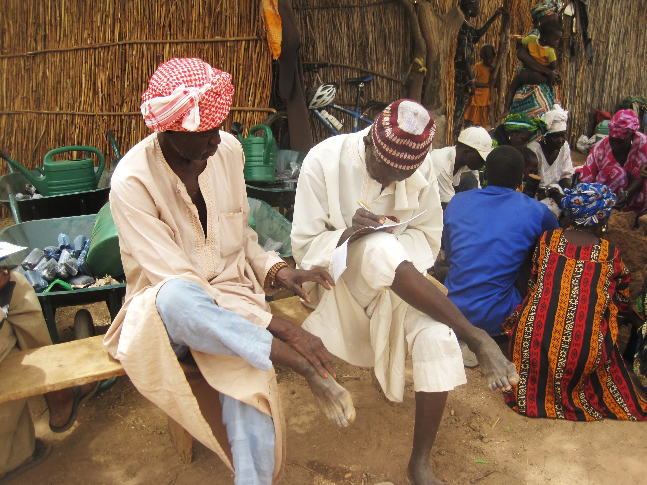 two women in a village selling items from the huts