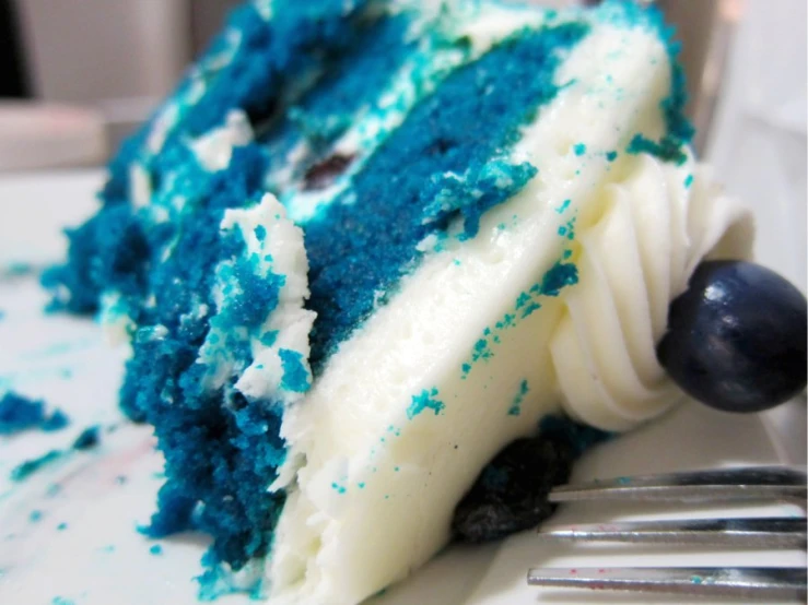 a blue velvet cake with white frosting and a bite taken out of it