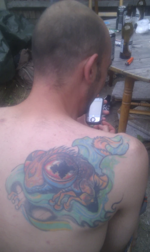 man with tattoos looking at cell phone screen