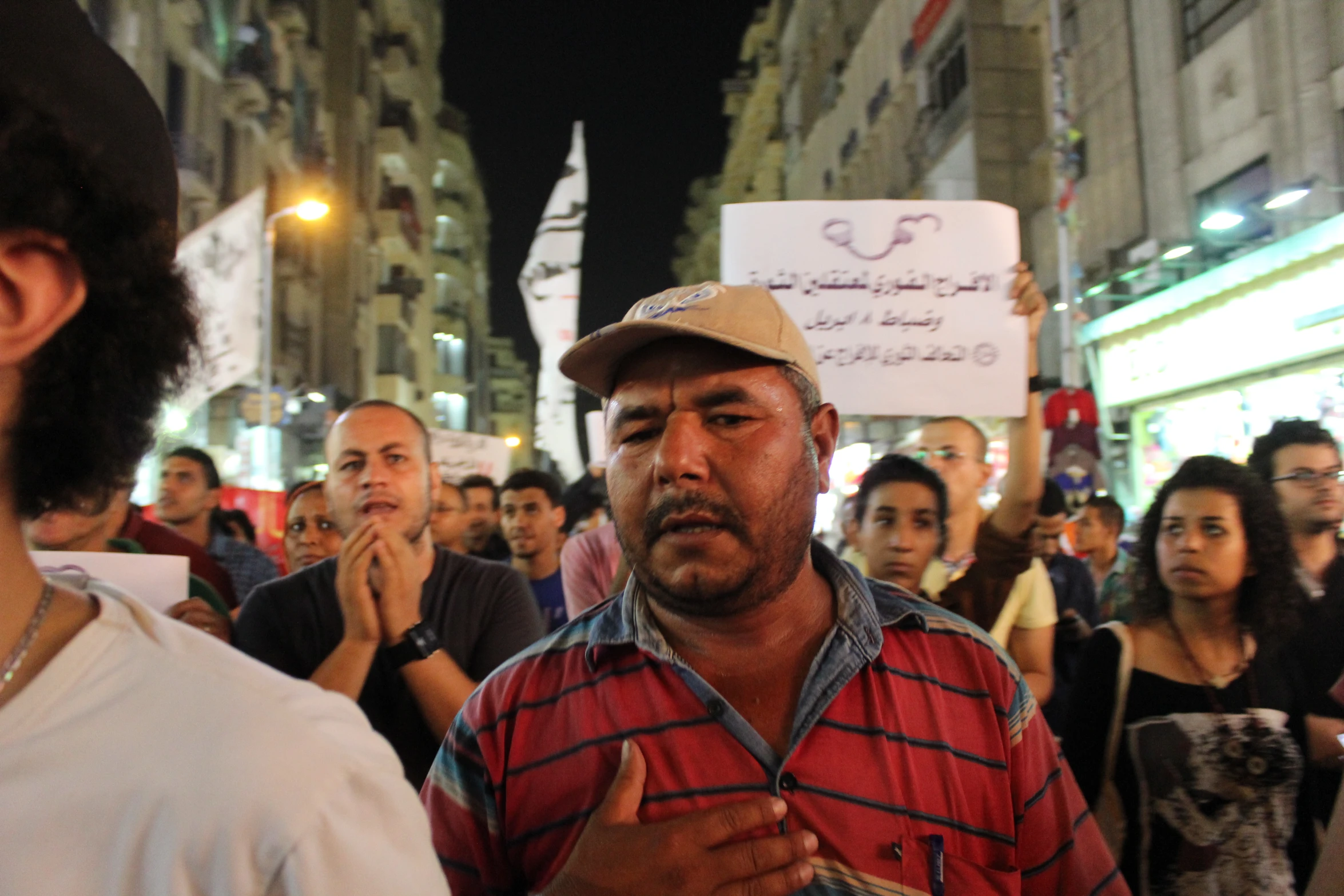 a man holding a protest sign standing in front of a crowd