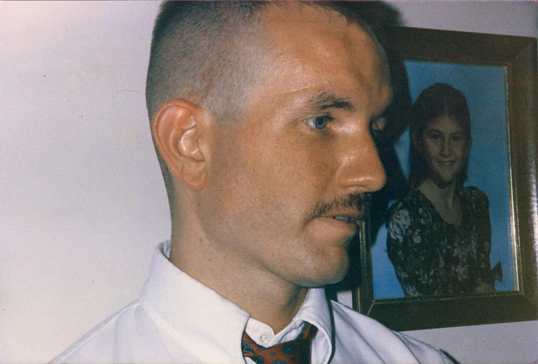 man wearing tie with large picture in background