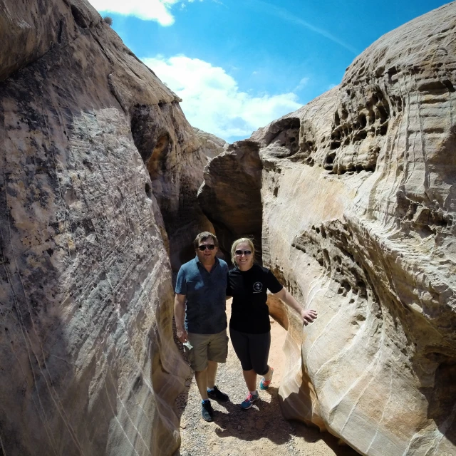 two people standing between a large  in the rock