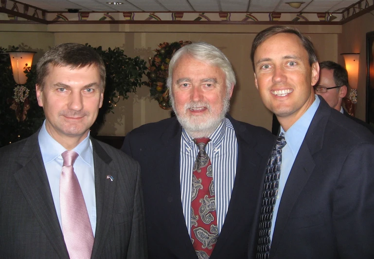 a trio of men are smiling together for the camera