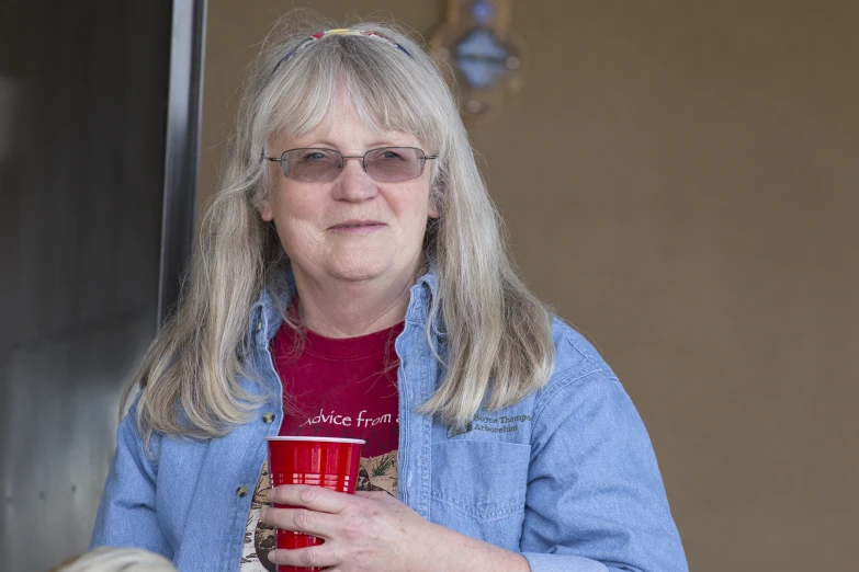a woman wearing glasses holding a red cup in her hand