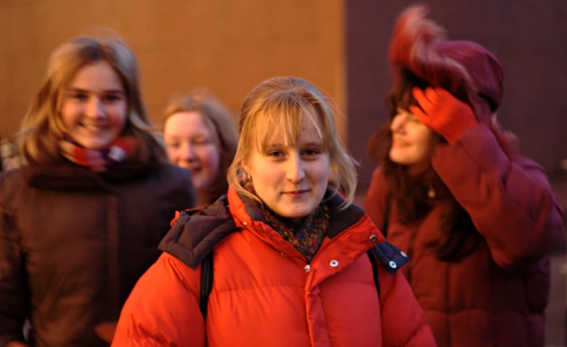 a girl in a coat and a girl in an orange jacket on the street