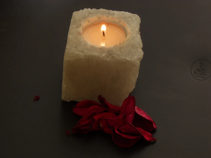 a candle is on the table with petals