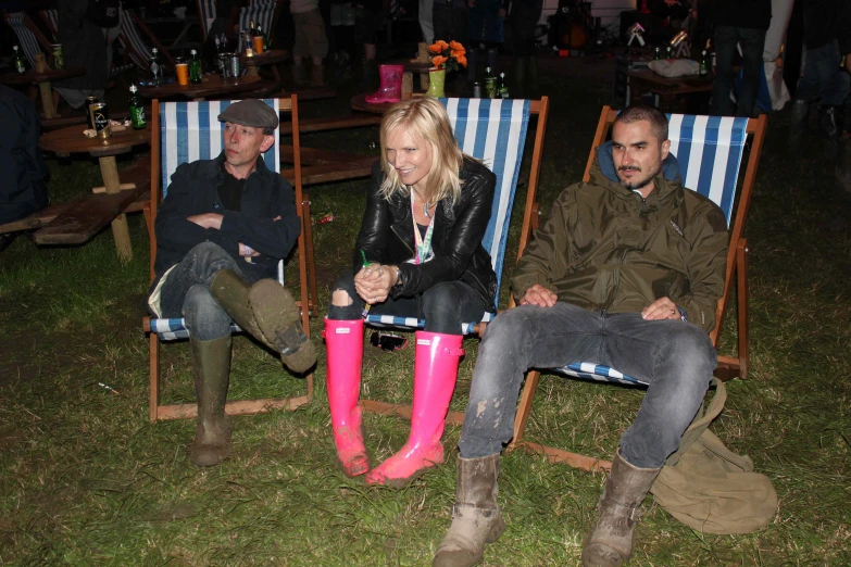 three people sitting on lawn chairs in a row