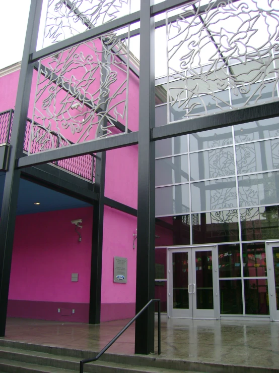 the entrance of the building has glass railing and is painted pink