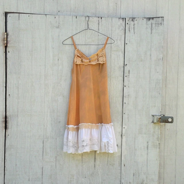 a beige and white dress on a hanger next to door